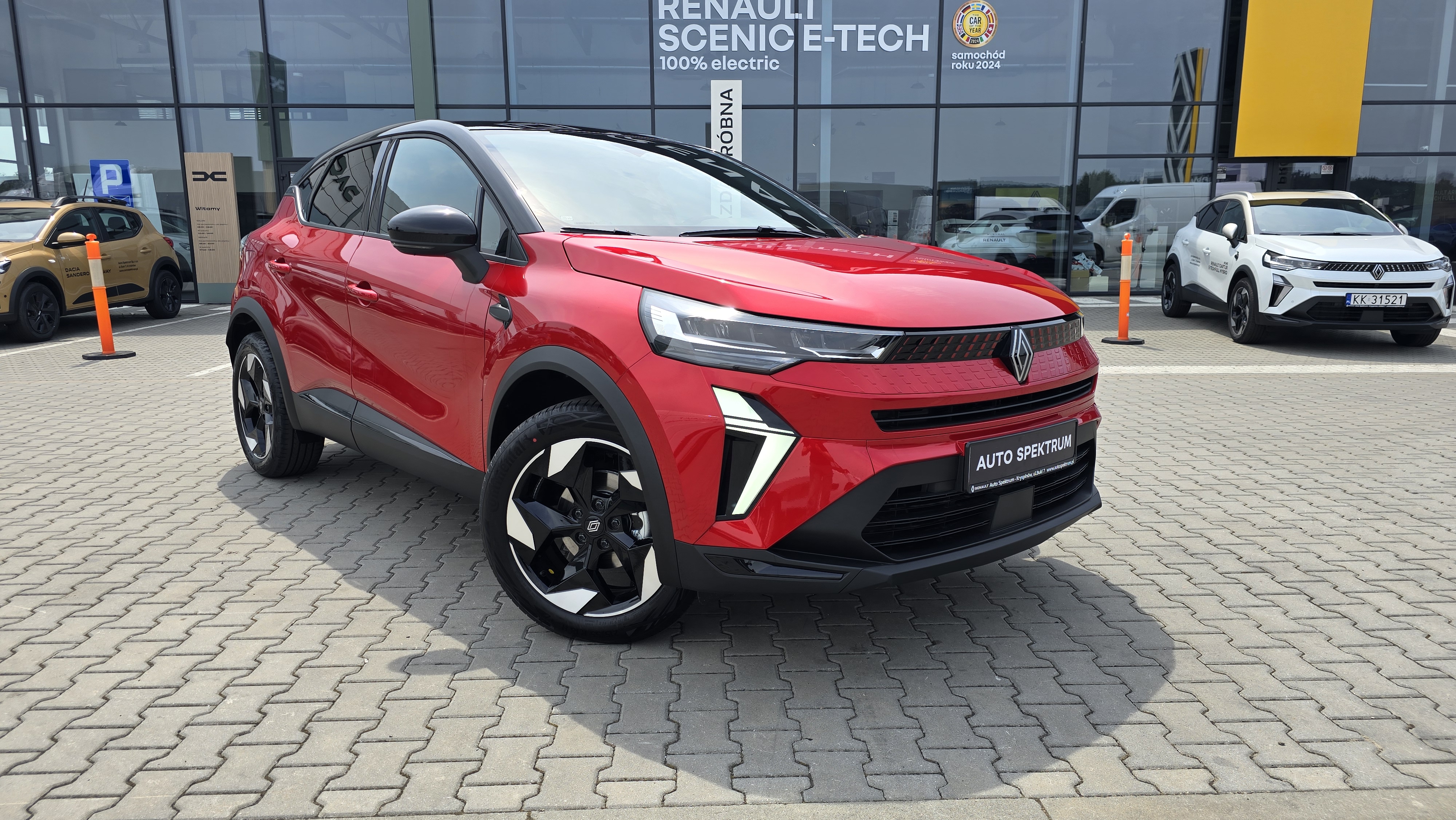 Renault Captur w czerwonym kolorze z czarnym dachem, na placu salonu Auto Spektrum w Rzeszowie.